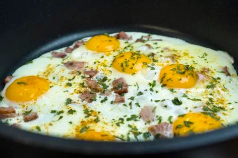 Fried eggs in a deep frying pan with bacon. Stock Photos