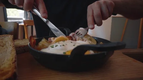 Fried eggs eating with fork and knife. Traditional breakfast eggs eating Stock Footage 79077225