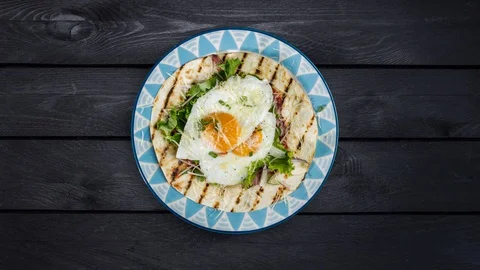 Fried eggs on flour tortilla with green salad and cheese rotating on a plate Stock Footage 129186850