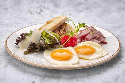 Fried eggs fried eggs with tomatoes, ham and ciabatta toast, on a white backg Stock Photos