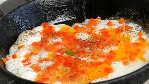 Fried eggs fried in pan with sweet pepper paprika greens. Morning breakfast Stock Footage 105802990