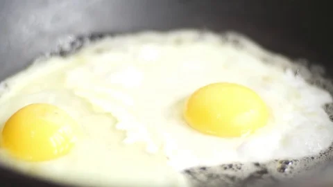 Fried eggs in a frying pan, sprinkled with spices, slow motion Stock Footage 83286812