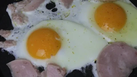 Fried eggs with ham in pan for breakfast top view Video stock 120236124