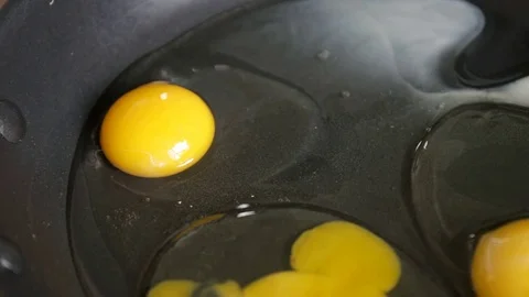 Fried eggs from a hen's egg in a black frying pan with yellow yolk Video stock 78733912