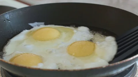 Fried eggs interfere with a spatula in a pan slowmotion Stock Footage