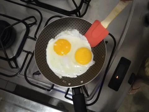 Fried eggs in a kitchen pan Stock Photos