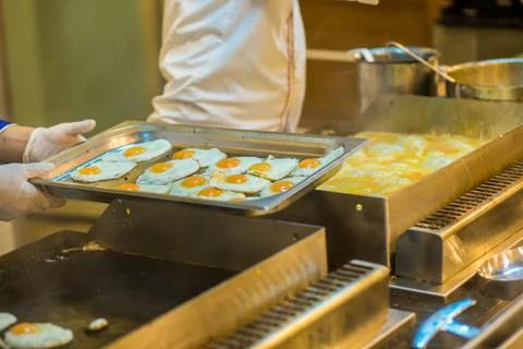 Fried eggs, a lot. The process of preparing breakfast in the buffet restauran Stock Photos