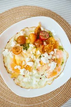 Fried eggs with marinated cherry tomatoes, herbs and feta cheese Stock Photos
