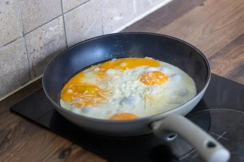 Fried eggs with melted cheese cooking in nonstick pan on induction stove Stock Photos