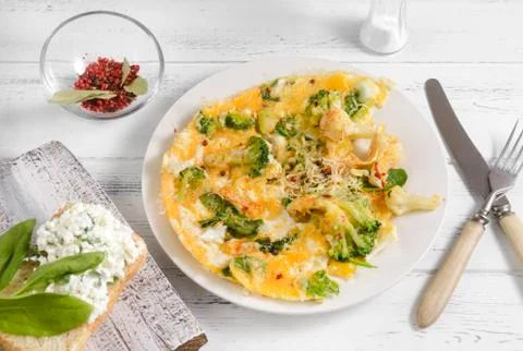 Fried eggs, omelette with spinach and broccoli and cheese on a plate on a whi Foto stock