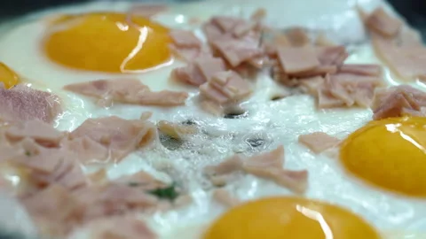 Fried eggs or omelette and with meat are fried in hot fat in kitchen frying pan Stock Footage 204070327