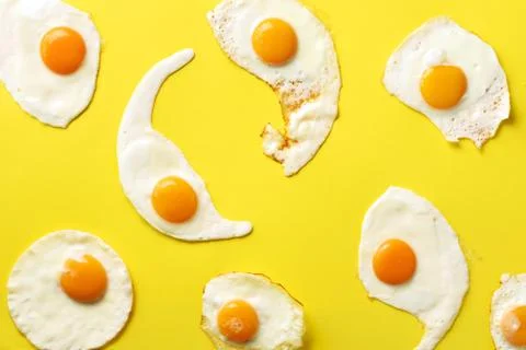 Fried eggs or scrambled eggs pattern on yellow background. Creative food concept Stock Photos