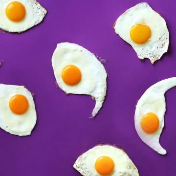 Fried eggs or scrambled eggs pattern on violet background. Creative food concept Stock Photos