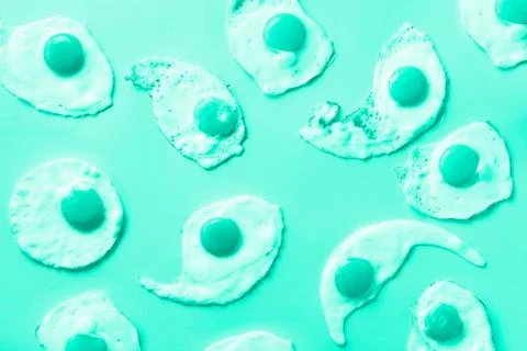 Fried eggs or scrambled eggs pattern on mint color background. Creative food Stock Photos