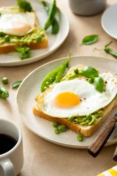 Fried eggs over bread toast with mashed avocado, coffee cups. Healthy breakfa Stock-Fotos