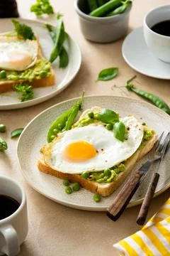 Fried eggs over bread toast with mashed avocado, coffee cups. Healthy breakfa Stock-Fotos