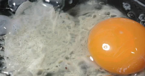Fried eggs in a pan. The broken egg falls into the frying pan Stock Footage 140688837