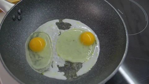 Fried eggs in a pan. Broken egg falls into the frying pan Stock Footage 142134076
