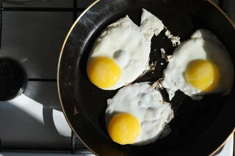 Fried eggs in a pan close-up Stock Photos