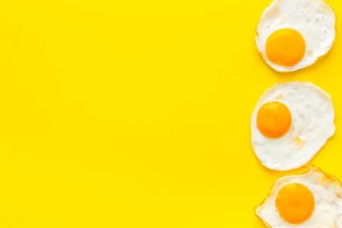 Fried eggs pattern on yellow background top view copy space Stock Photos