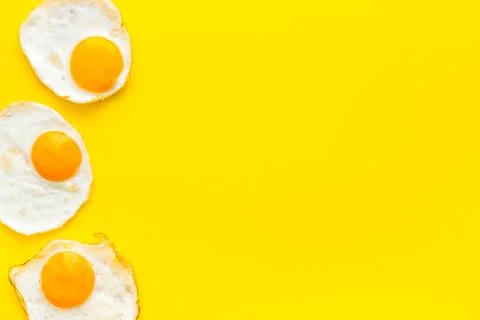 Fried eggs pattern on yellow background top view copy space Stock Photos