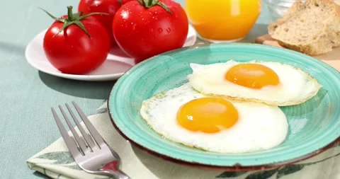 Fried eggs on a plate. breakfast with fresh vegetables and bread on the table. Stock Footage 241954877