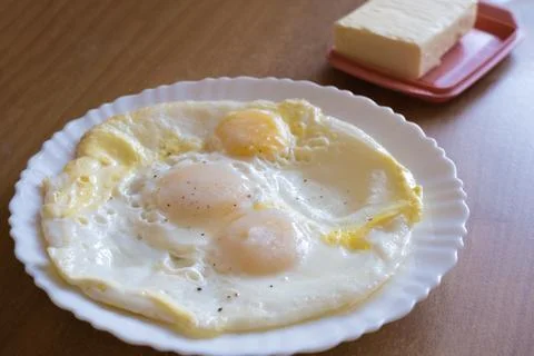 Fried eggs in a plate on the table. Breakfast on the table. Stock Photos