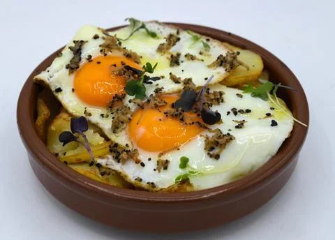 Fried eggs with potatoes on a white background Stock Photos