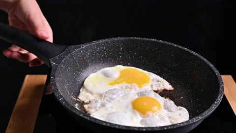 Fried eggs in a skillet with butter. Eggs for a traditional breakfast. 動画素材 145698270