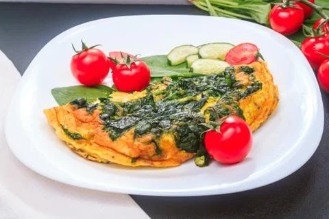 Fried eggs with spinach and tomatoes, cucumbers on a white large plate on a Stock Photos
