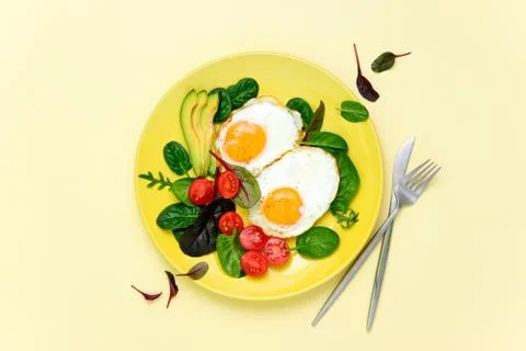 Fried eggs with spinach tomatoes and greens Stock Photos