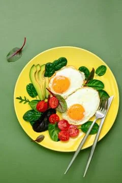 Fried eggs with spinach tomatoes and greens Stock Photos
