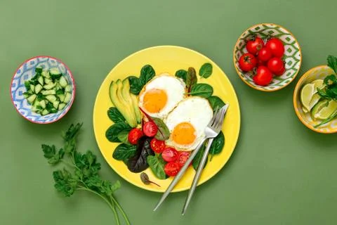 Fried eggs with spinach tomatoes and greens Stock Photos