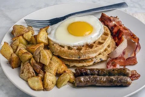 Fried eggs on stack waffles   with home fries Stock Photos