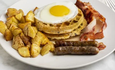 Fried eggs on stack waffles   with home fries Stock Photos