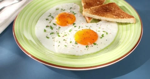 Fried eggs with toast on a green plate. close-up. angle view. camera tracking. Stock Footage 241456089