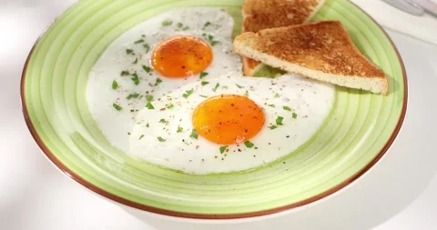 Fried eggs with toast on a green plate. close-up. angle view. camera tracking. Stock Footage 243043533