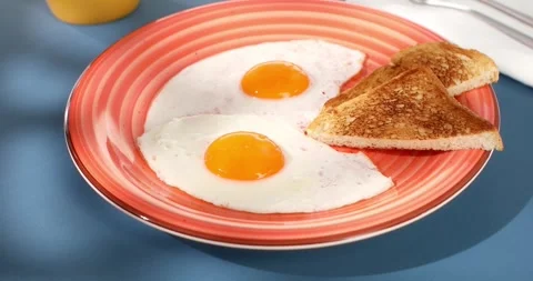 Fried eggs with toast on a red plate. close-up. angle view. camera tracking. Stock Footage 244640077