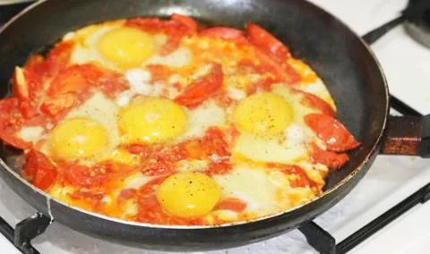 Fried eggs with tomato on the pan Stock Photos