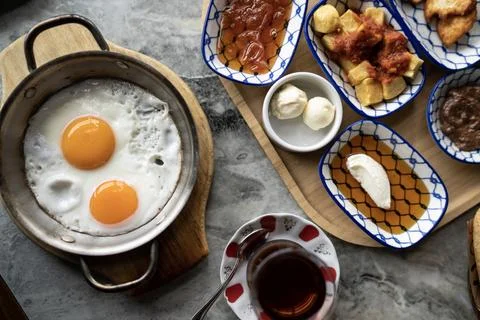 Fried eggs, Turkish tea and breakfast bowls on marble, flat lay Stock Photos