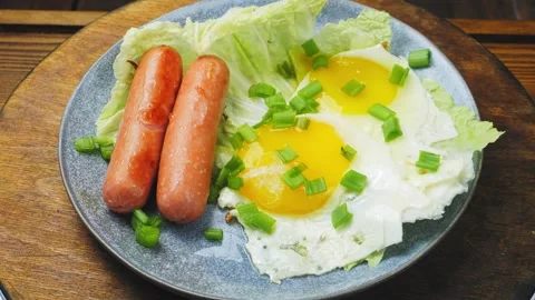 Fried eggs of two eggs with sausages sprinkled with green onions on a plate.. Stock Footage 274223617