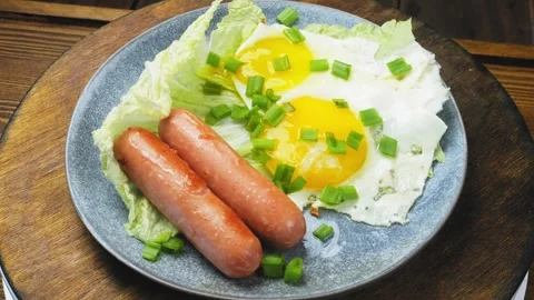 Fried eggs of two eggs with sausages sprinkled with green onions on a plate.. 库存影片 275193039