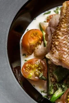 Fried fish accompanied by keabos and tomatoes seen from above. Gourmet dish. Stock Photos