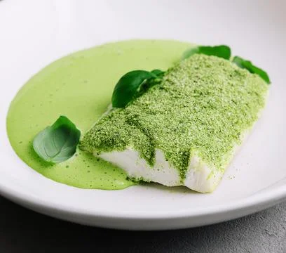 Fried fish with basil sauce on plate Stock Photos