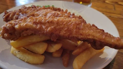 Fried fish being served on top of chips. Traditional English food Stock Footage 291323847