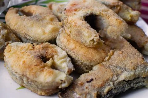 Fried fish in breading on a plate. Stock Photos