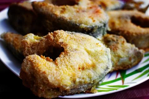 Fried fish in breading on a plate. Stock Photos