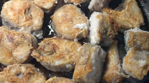 Fried fish in flour in a dark pan, appetizing golden crust, home kitchen Stock Footage 336402804