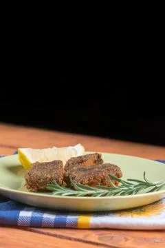 Fried fish on the plate with lemon and rosemary with black background Stock Photos