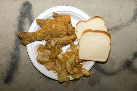 Fried fish with potatoes and bread on plate Foto stock